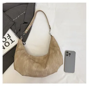 Detail of khaki hobo bag with pleated texture and thin strap next to a phone for size