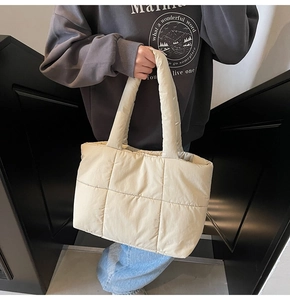 Detail of beige quilted puffer tote bag showing soft nylon texture and large grid pattern