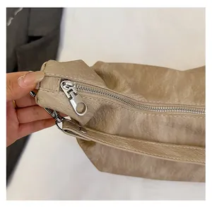 Detail of silver zipper and lychee grain leather on beige shoulder bag