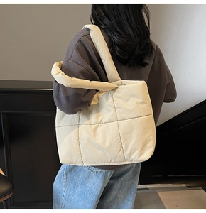 Quilted cream puffer tote bag detail showing wide shoulder strap and soft nylon texture