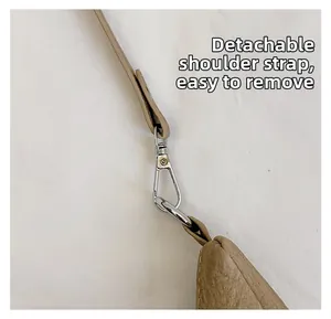 Detail of a brown textured leather bag featuring a detachable strap with silver metal hooks