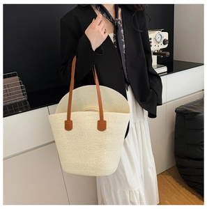 Detail of off-white woven straw tote bag with brown leather straps and matching sun hat