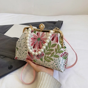Elegant floral embroidery handbag with pearl handle and metal clasp in a side view