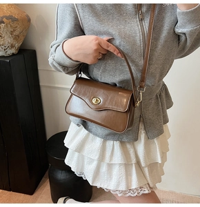 Détail d'un sac à bandoulière en cuir marron avec un fermoir rotatif en métal doré chic