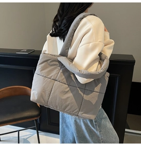Detailed back view of a grey quilted puffer tote bag worn by a model for daily commute