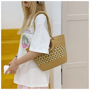 Detail einer Vintage Strohtasche mit geometrischen Mustern und Lederklappe am Modell