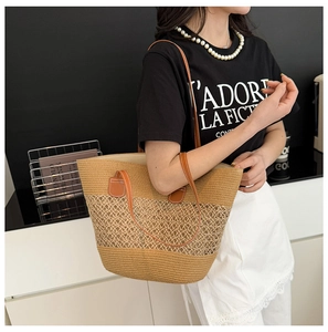 Detailed shot of large straw tote bag with mesh design and brown leather handles