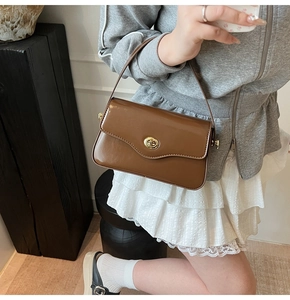 Détail du sac bandoulière en cuir marron foncé brillant avec fermoir rotatif doré élégant
