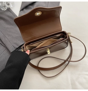 Détail du sac à bandoulière marron foncé avec deux compartiments et fermoir doré