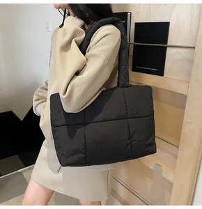 Detailed side view of large black quilted tote bag worn by a model for a stylish look