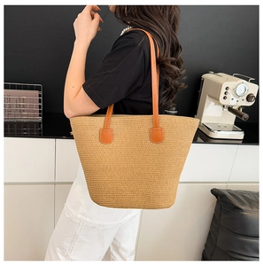 Detail view of khaki straw woven tote bag with orange synthetic leather handle details