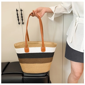 Close-up of four-color striped straw tote bag featuring brown faux leather handles