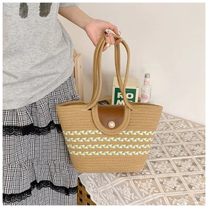 Detail der Strohtasche mit farbigen Streifen, Lederklappe und elegantem Perlenverschluss