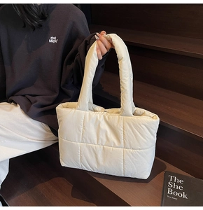 Close-up of a quilted off-white tote bag with a soft padded texture and square stitching
