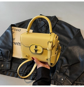 Detail of yellow lychee leather handbag with golden oval twist lock and sturdy handle