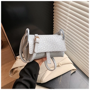 Détail de la texture tissée bleu clair et boucle dorée sur un petit sac carré chic