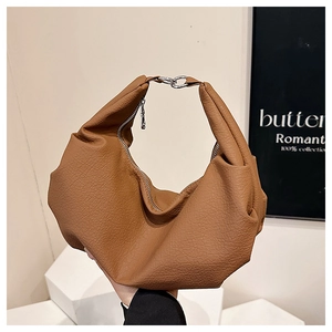 Close-up of caramel brown soft leather bag featuring a silver metal ring buckle detail