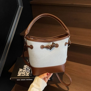 Retro canvas and leather bucket bag with olive wood buckle on wooden stairs