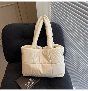 Detailed view of quilted puffer tote bag with diamond stitching on a vintage chair