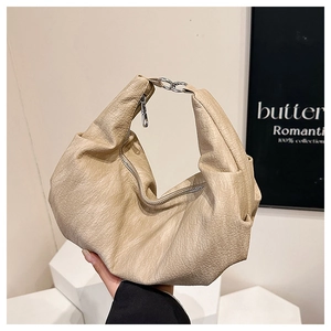 Detail of beige soft leather dumpling bag showing textured PU material and silver rings
