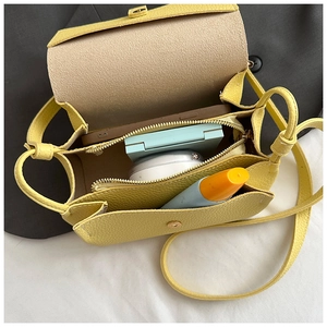 Internal view of yellow cross-body bag showing capacity for phone and cosmetics
