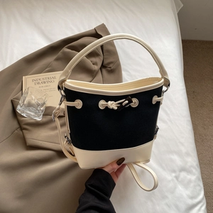 Minimalist canvas bucket bag with contrast leather trim and toggle closure detail