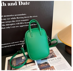 Macro view of bright green mini crossbody bag with smooth matte leather texture