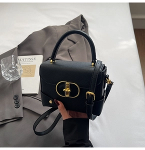 Detail of lychee pattern leather and gold metal lock on black crossbody bag