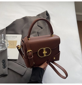Detailed view of brown litchi grain leather handbag featuring elegant gold metal lock