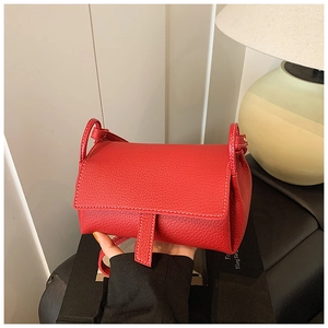 Close-up of red lychee pattern leather handbag with white contrast stitching detail