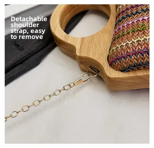 Detalle de la correa de cadena dorada desmontable en un bolso tejido de colores