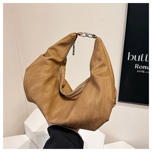Detail of caramel pleated leather bag showing silver metal ring buckle and zip closure