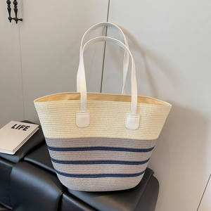 Detail of a large woven tote bag featuring cream and blue stripes with white leather straps
