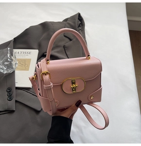 Detail of pink lychee leather handbag with gold metal lock and reinforced base studs