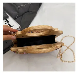 Detalle interior de un bolso tejido con asa de bambú y correa de cadena dorada