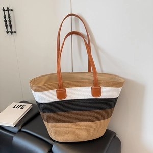 Detail of multi-color straw tote featuring brown leather handles and woven texture