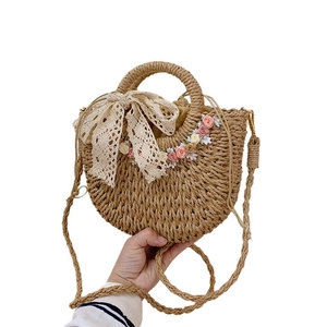 Handwoven straw shoulder bag with floral lace bow decoration and drawstring closure