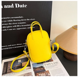 Detail of bright yellow mini tote bag with top handles and adjustable shoulder strap