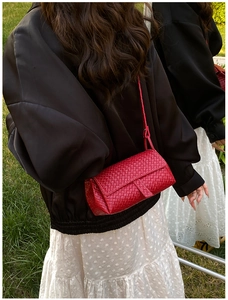 Détail du sac à bandoulière en cuir tressé rouge avec texture brillante et rabat
