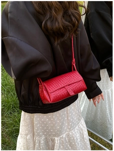 Gros plan détaillé d'un sac bandoulière rouge à texture tressée et rabat rectangulaire