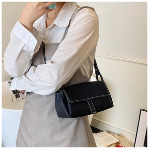Detail of black lychee grain leather shoulder bag featuring vintage white contrast stitching