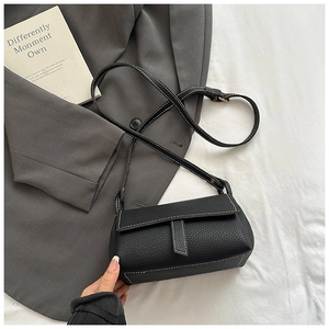 Close-up of black lychee grain leather crossbody bag with white contrast stitching details