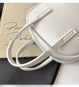 Detail of white leather handbag with sturdy dual handles and premium metal zipper closure