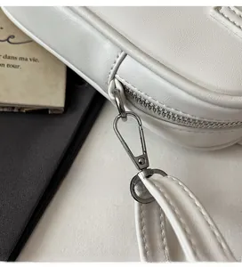 Macro detail of white leather handbag showing fine stitching and silver metal hardware