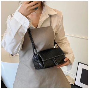 Détail d'un sac porté épaule noir tissé avec surpiqûres blanches contrastées au style épuré