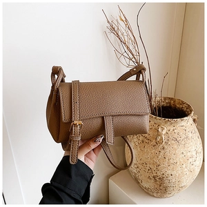 Close-up of brown litchi grain leather crossbody bag with golden hardware and flap design