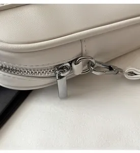 Macro shot of smooth silver metal zipper and cream leather texture on the bag