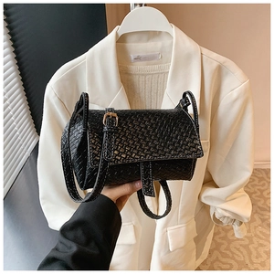 Détail du sac à bandoulière tressé noir avec coutures contrastées blanches et boucle dorée