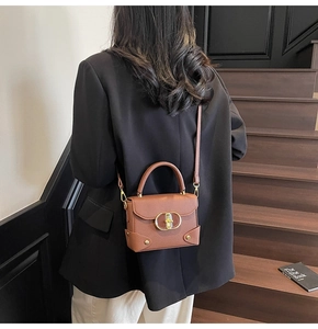 Close-up of brown pebbled leather bag with gold buckle on a stylish model