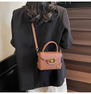 Detail of vintage brown pebble leather handbag featuring a gold CD style lock buckle